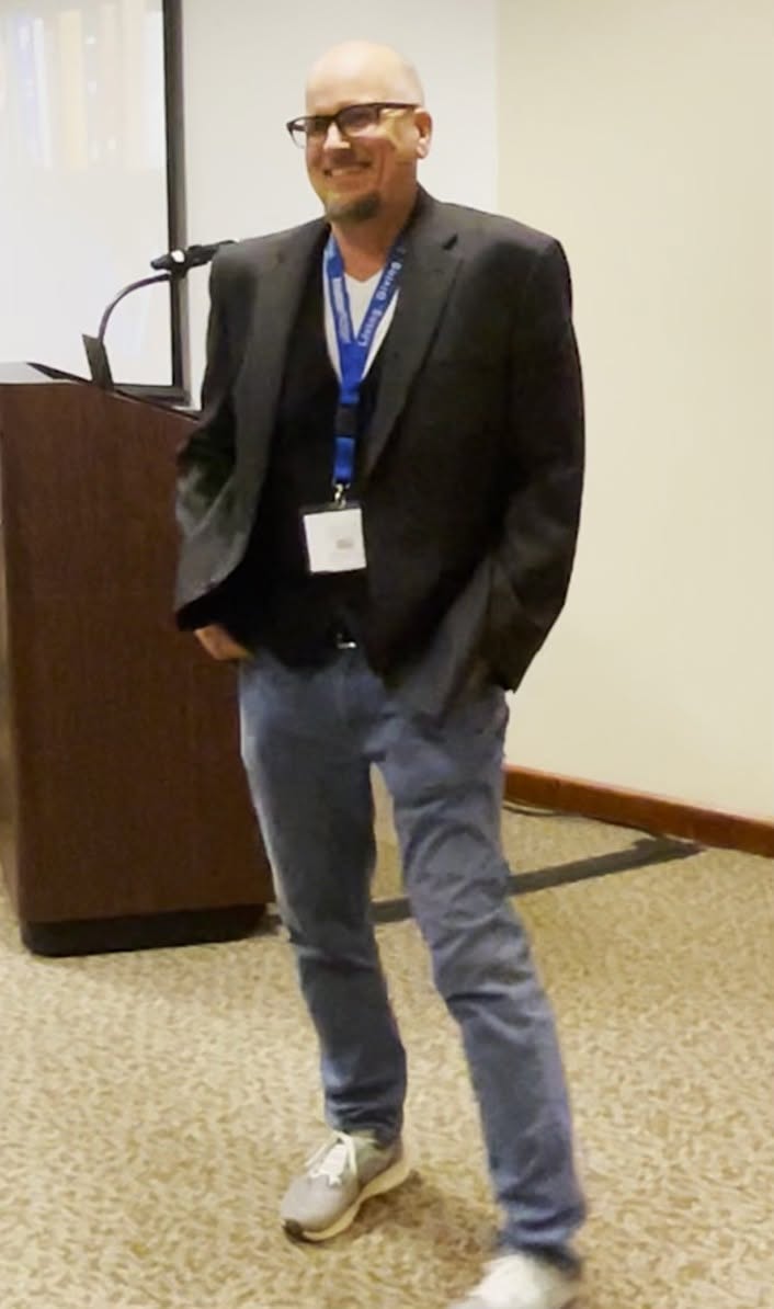 Tommy Onyx smiling beside the presentation podium